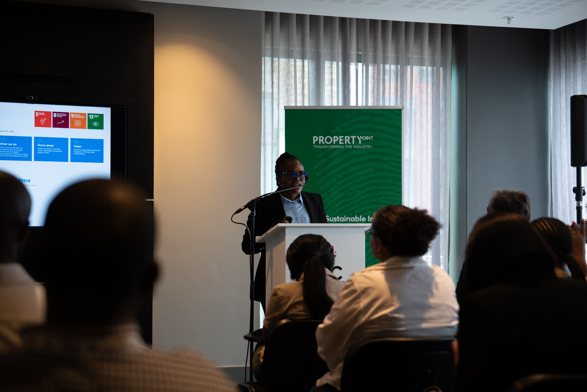 Wooden shelf with gray and olive drab green baseball caps, next to wooden clothes hanger with sweaters.